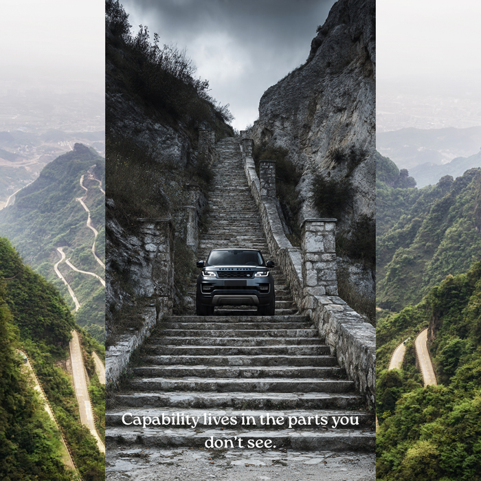 Land Rover Defender climbing a steep stone stairway between rocky mountain cliffs, demonstrating off-road engineering capability